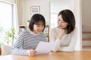 明るいリビングで、中学生の子どもと保護者が成績表を一緒に見ながら穏やかに話し合っている様子