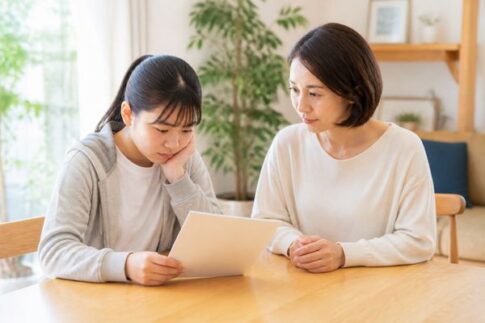 明るいダイニングで通知表を一緒に見つめる中学生と保護者