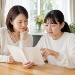 明るいダイニングテーブルで母親と中学生の娘が成績表を一緒に見ている様子