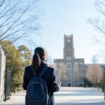 志望校の大学の門の前に立ち出願を考える受験生
