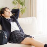 テストを終えて自宅のソファでくつろぐ制服姿の高校生