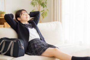 テストを終えて自宅のソファでくつろぐ制服姿の高校生