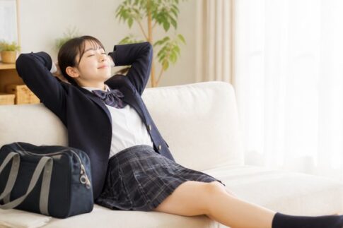 テストを終えて自宅のソファでくつろぐ制服姿の高校生