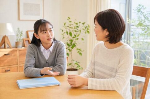 通知表の成績2について自宅で母親と話し合う高校生の女子生徒