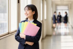 テスト返却後の明るい校舎の廊下で、5教科の答案ファイルを胸に抱えて静かに喜ぶ制服姿の中学生
