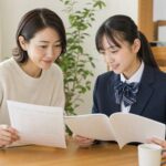 明るいダイニングで、成績表と高校案内を並べて一緒に見ている中学生と保護者