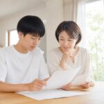 自宅のダイニングで中学生の息子と母親が通知表と資料を一緒に確認している様子