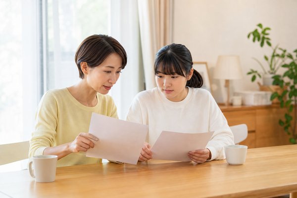 明るいリビングで通知表と模試の結果を見比べる母親と中学生の娘