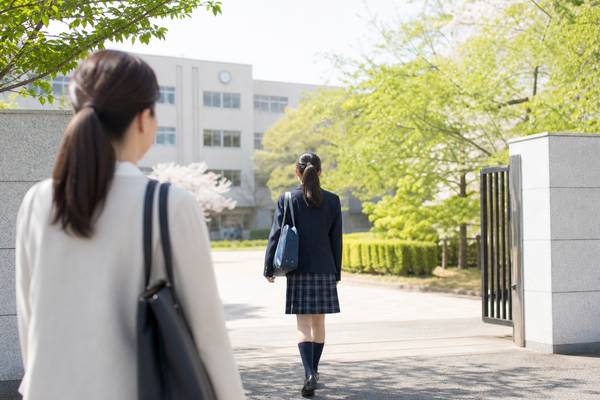高校受験を控えた中学生と、その後ろ姿を見守る保護者。偏差値と内申点をどう見るかを考える場面