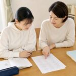 模試の答案を一緒に見ながら、取り戻せる失点を確認する高校生と保護者
