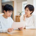 返却されたテストを手に、保護者と次に何を直すかを話している中学生