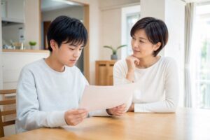 返却されたテストを手に、保護者と次に何を直すかを話している中学生