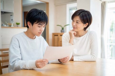 返却されたテストを手に、保護者と次に何を直すかを話している中学生