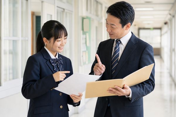 返ってきた答案を見ながら、先生と成績の上げ方を確認している中学生