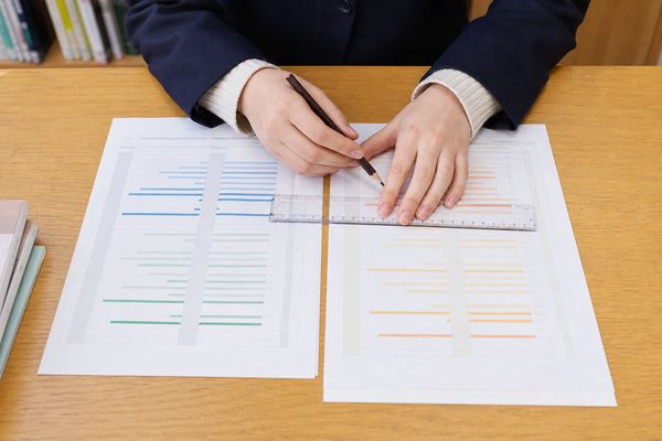 2種類の判定資料を並べて共通テストのC判定の基準を照合する高校生の手元