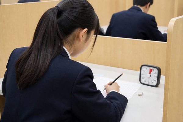 タイマーを置き、本番と同じ時間で問題を解く制服姿の女子高校生