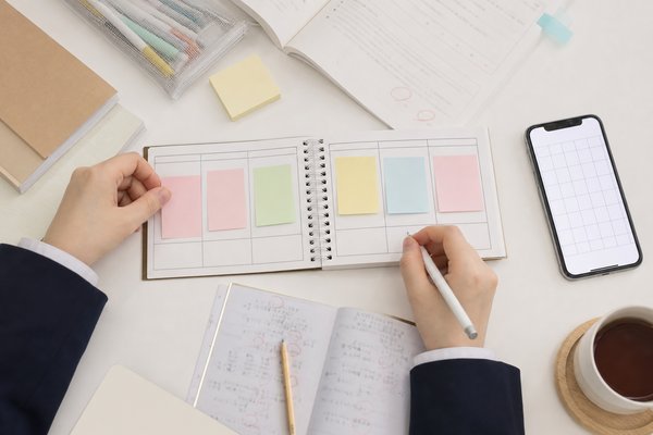 付箋と復習ノートを使って週ごとの学習計画を立てる高校生の手元