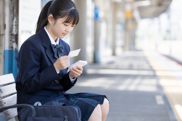 制服姿の中学生が通学途中のベンチで、覚えきれていない一問を集めた暗記カードを確認している様子