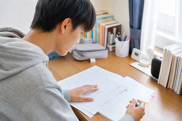 自宅の机で二次試験の過去問の失点を付箋と色分けで見直している受験生