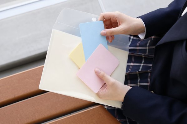制服姿の生徒が3色のカードをクリアファイルに整理する様子