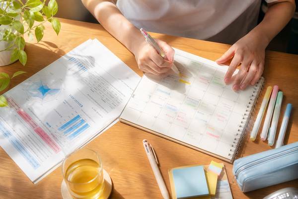 模試の個人成績表を見ながら夏休みにやることを手帳へ書き込んでいる高校生の手元