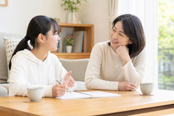 明るいリビングで1冊のノートを前に、母親が聞き役になって週に一度の振り返りをしている親子