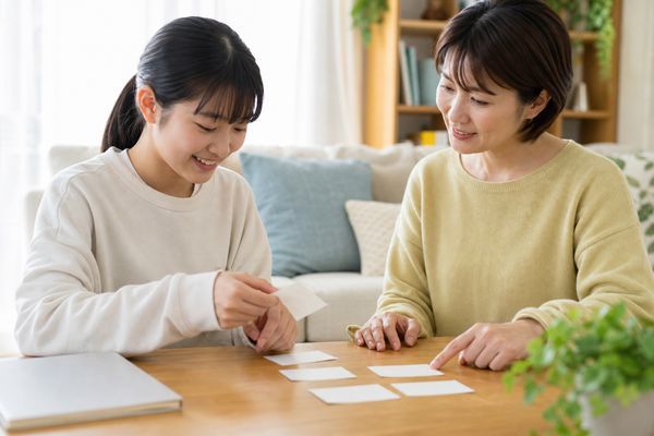 リビングでカードを並べ子どもと一緒に振り返る母親と中学生