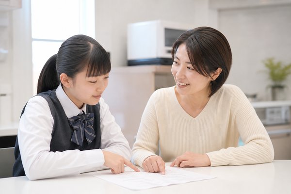 明るいキッチンで母親と中学生が答案を一緒に見ながら話し合う場面