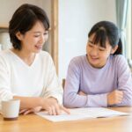 明るいダイニングで通知表を一緒に見ながら笑顔で話す母親と中学生の娘