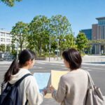 進路の分かれ道で高校と大学の資料を見比べる高校生と保護者