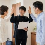 通知表を手に帰宅し、両親とハイタッチして喜び合う制服の中学生