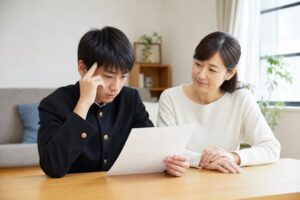 答案を見つめる中3の男子生徒と、隣で静かに見守る母親