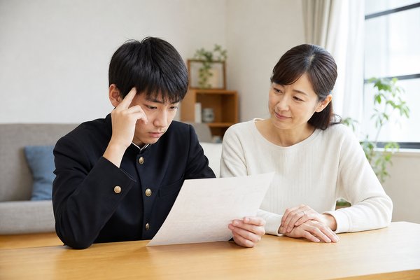 答案を見つめる中3の男子生徒と、隣で静かに見守る母親