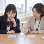 進路相談室で先生と選抜方式のカードを並べて話し合う高校生