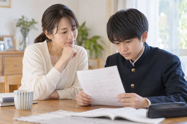 答案を前に、母親と中学生の息子が個別指導塾の成果について話している場面