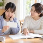 受験票を手に不安そうな表情の中学生と、英語の過去問を開いて指さす保護者