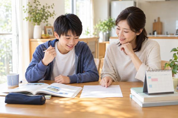 ダイニングテーブルで中1の男子生徒と母親が英語のテスト範囲表を一緒に確認している様子