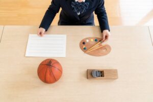 音楽・美術・保健体育・技術家庭の道具を机に並べる制服の中学生