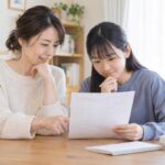 ダイニングテーブルで母親と中学生の娘が返却された答案を一緒にのぞき込みながら穏やかに話している様子