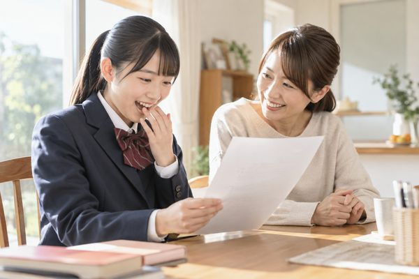 返却されたテストを見て驚きながら喜ぶ中学生と保護者