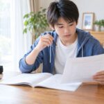 範囲表と数学の問題冊子を見比べて1回分を選ぶ中学2年生