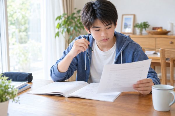 範囲表と数学の問題冊子を見比べて1回分を選ぶ中学2年生