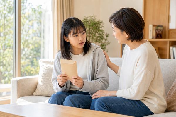合格通知の封筒を手に、三学期の成績について母親と話す中3の生徒