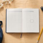 机に広げた学生鞄と予定カレンダー、鉛筆と腕時計を真上から写した写真