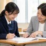 教室で先生と一緒に通知表と返却物を見ながら、内申を上げる方法を確認する中学生