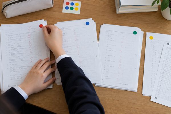 返却された英語の答案を机に広げ、失点の原因ごとに4色の丸シールを貼って仕分けている中学生の手元