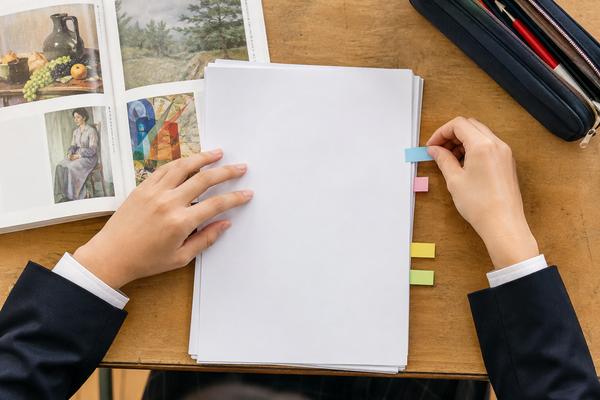 美術資料を横に置き、テスト範囲表に色付き付箋を貼る中学生の手元