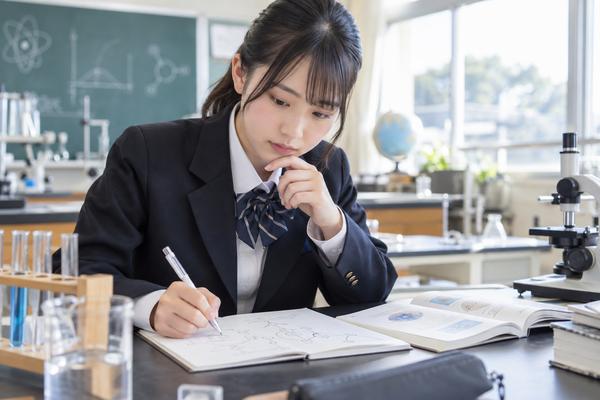 理科室で応用問題の図をかきながら考え込む制服姿の女子高校生