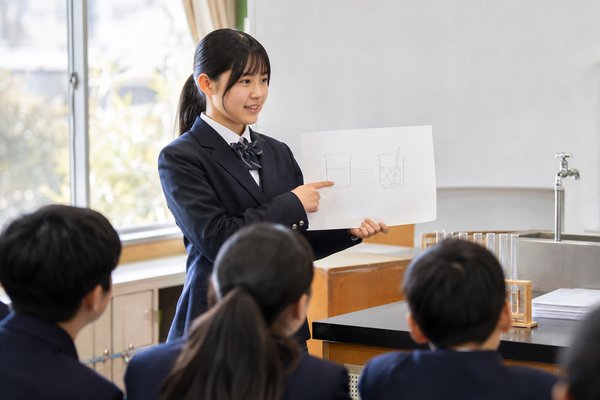 理科室で実験結果の図を示しながら根拠を説明する制服の女子中学生