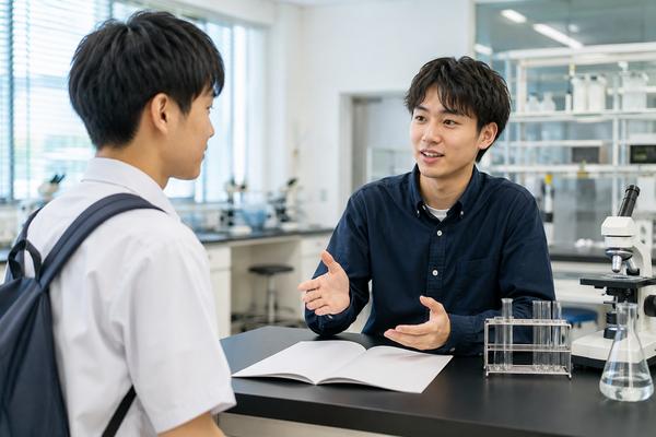 大学のオープンキャンパスで実習室の学びを大学生から説明してもらう高校生